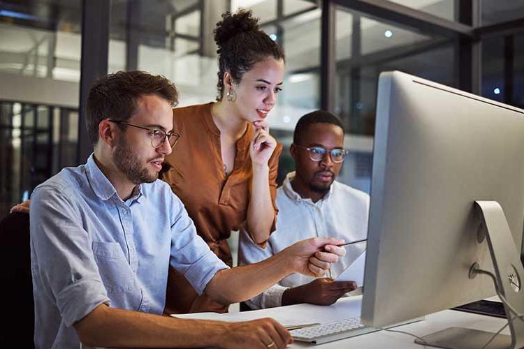 Three people looking at a computer screen together.